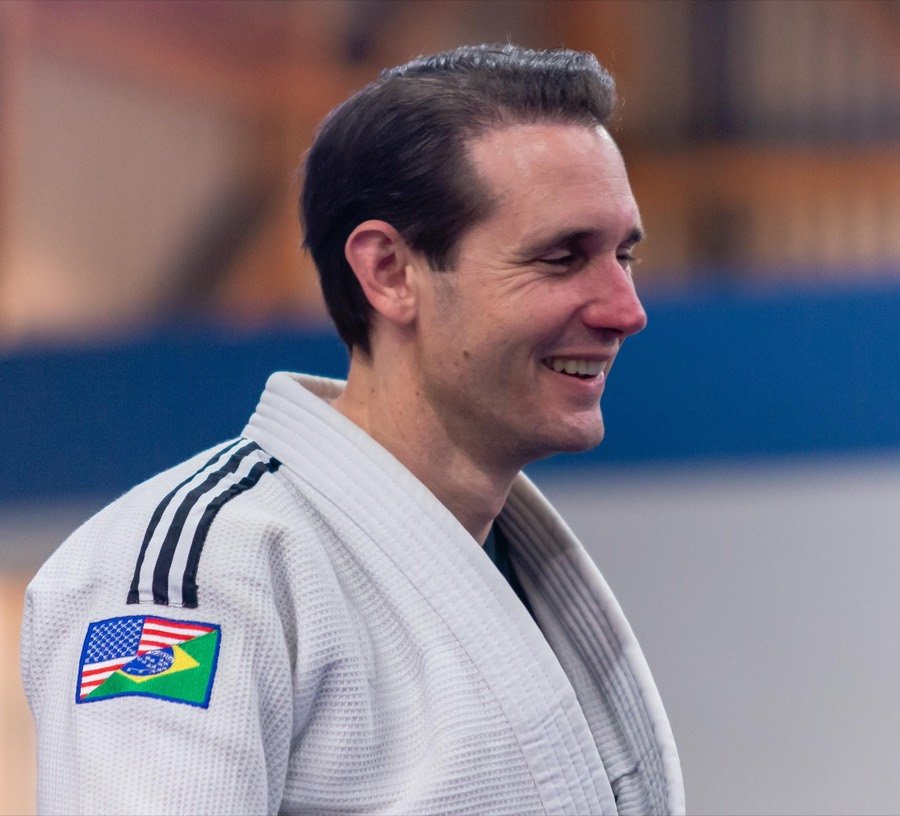 Coach Christopher Fraze smiling in a white judogi