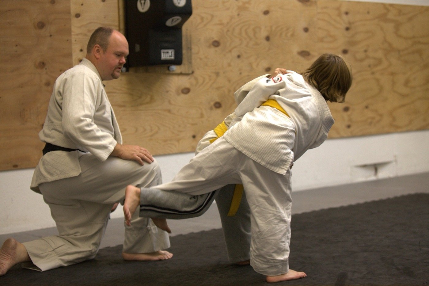A coach kneels beside a student to adjust her throwing technique